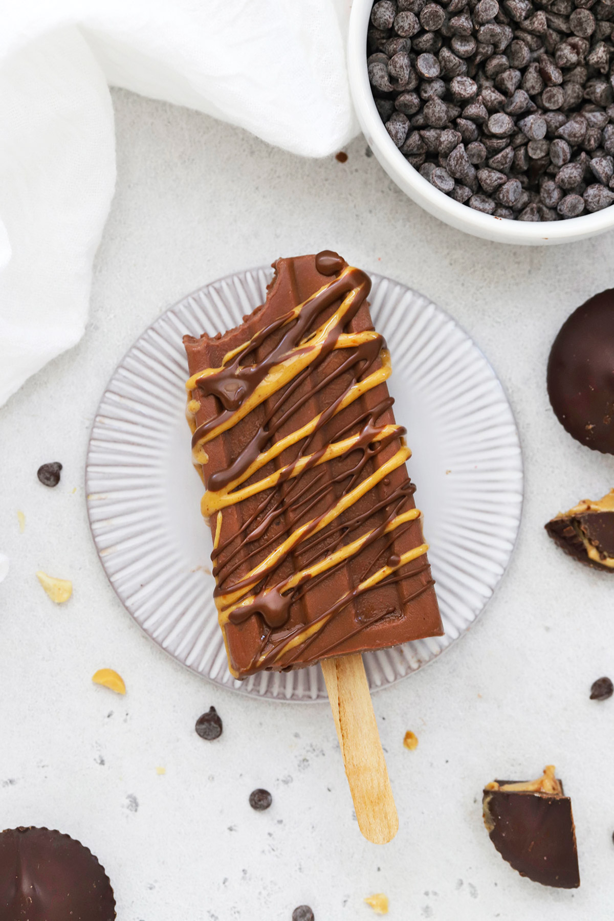 Overhead view of a chocolate peanut butter popsicle drizzled with natural peanut butter and healthy chocolate shell