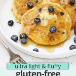 Front view of 3 fluffy gluten-free blueberry pancakes on a white plate drizzled with syrup with text overlay that reads "the ultimate light & fluffy gluten-free blueberry pancakes: dairy-free friendly + delicious"