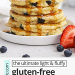 Front view of a stack of fluffy gluten-free blueberry pancakes being drizzled with syrup with text overlay that reads "the ultimate light & fluffy gluten-free blueberry pancakes: dairy-free friendly + delicious"
