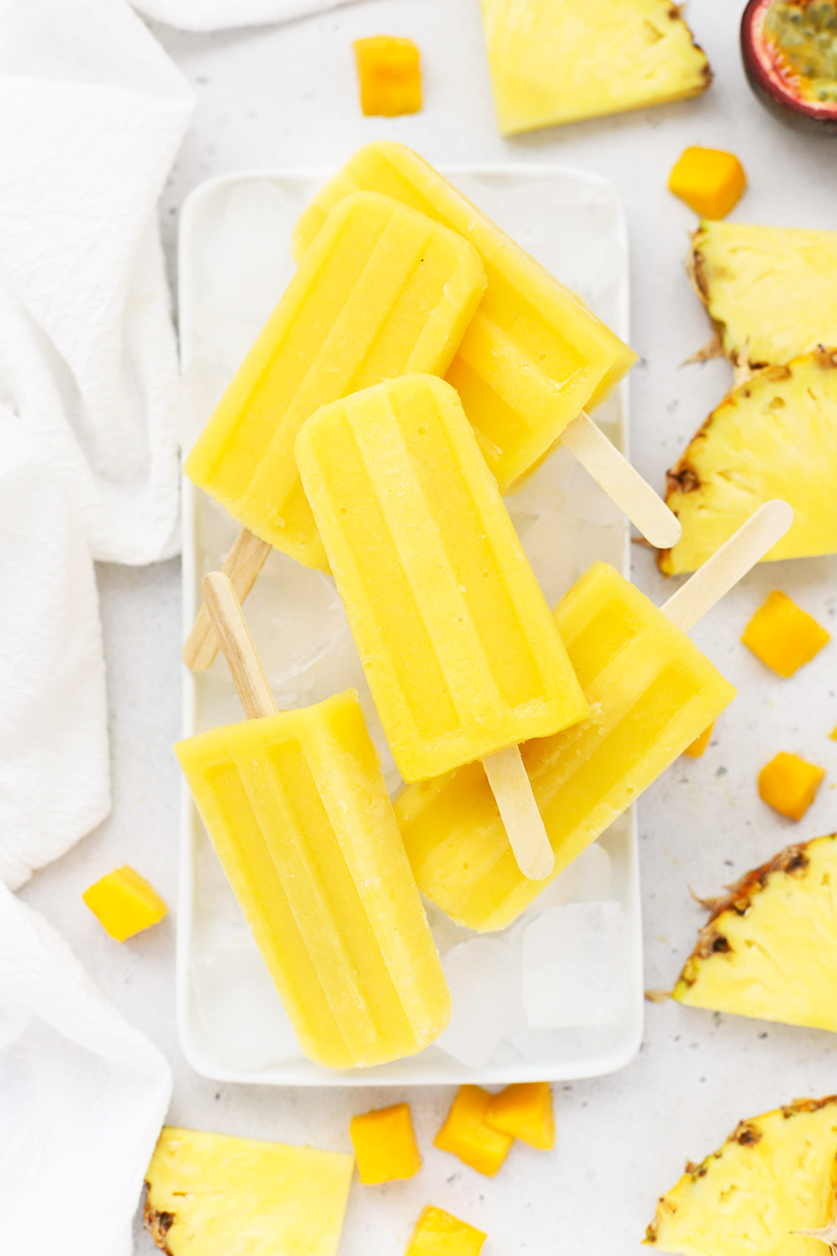 Overhead view of mango passion fruit popsicles stacked on a plate of ice