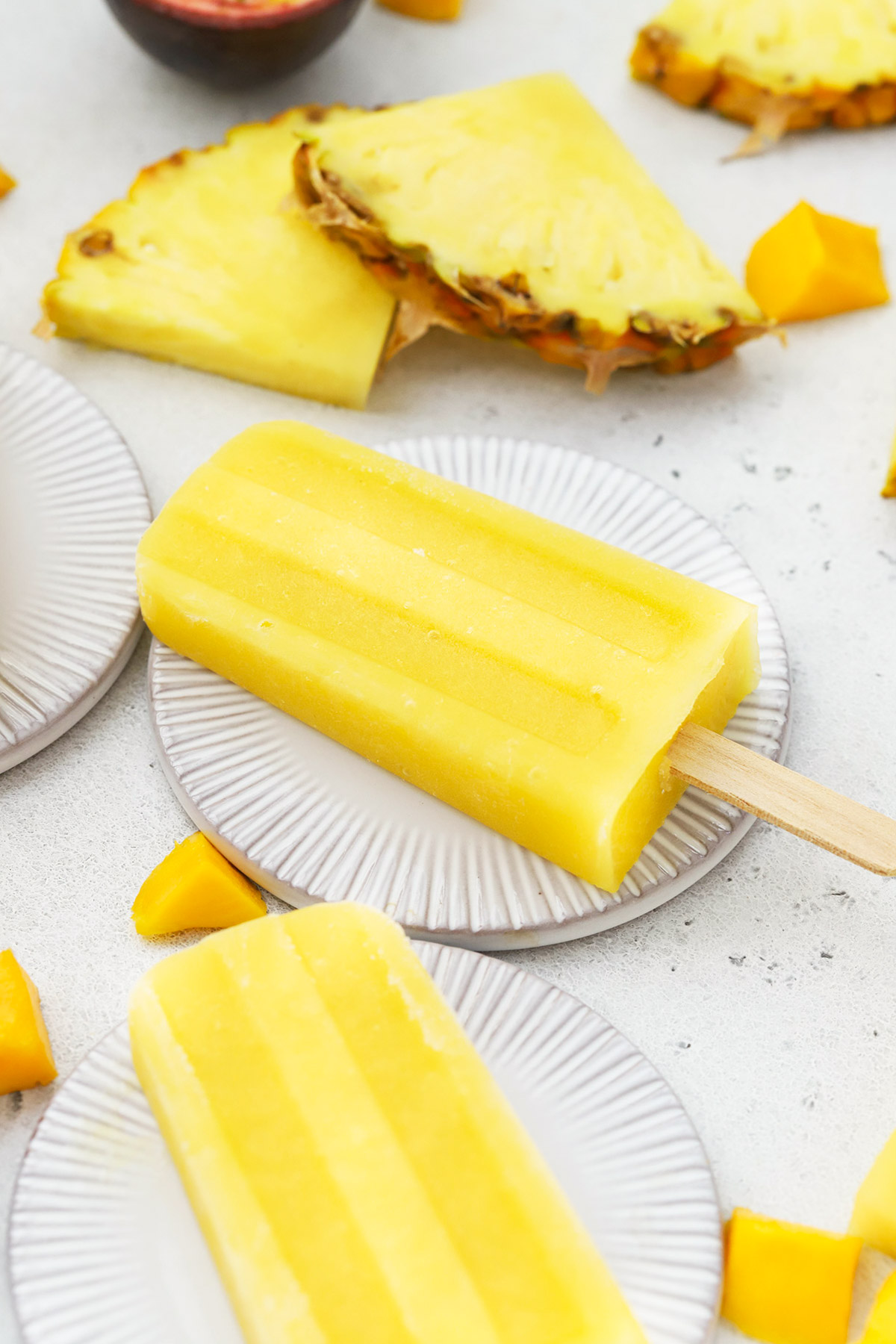 Front view of three mango passion fruit popsicles on coasters