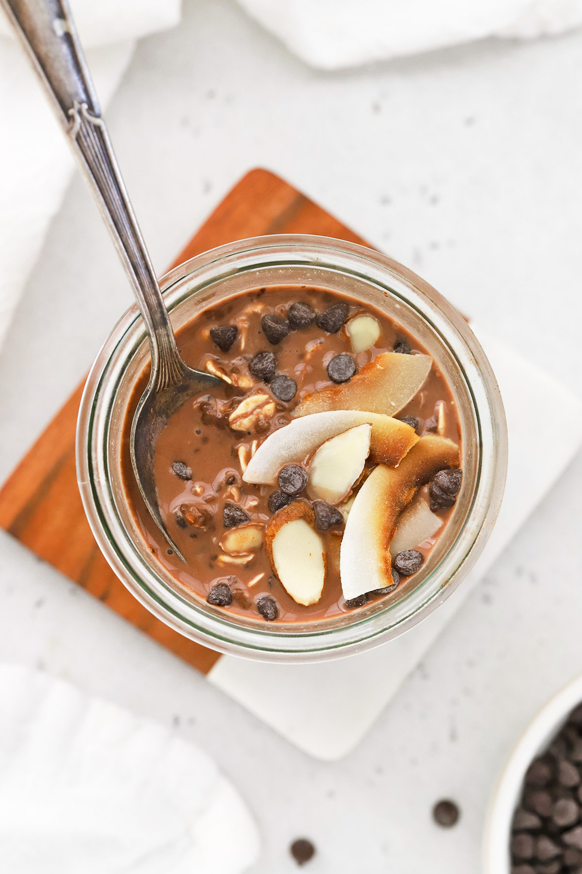 Overhead view of a jar of almond joy overnight oats topped with chocolate and coconut.