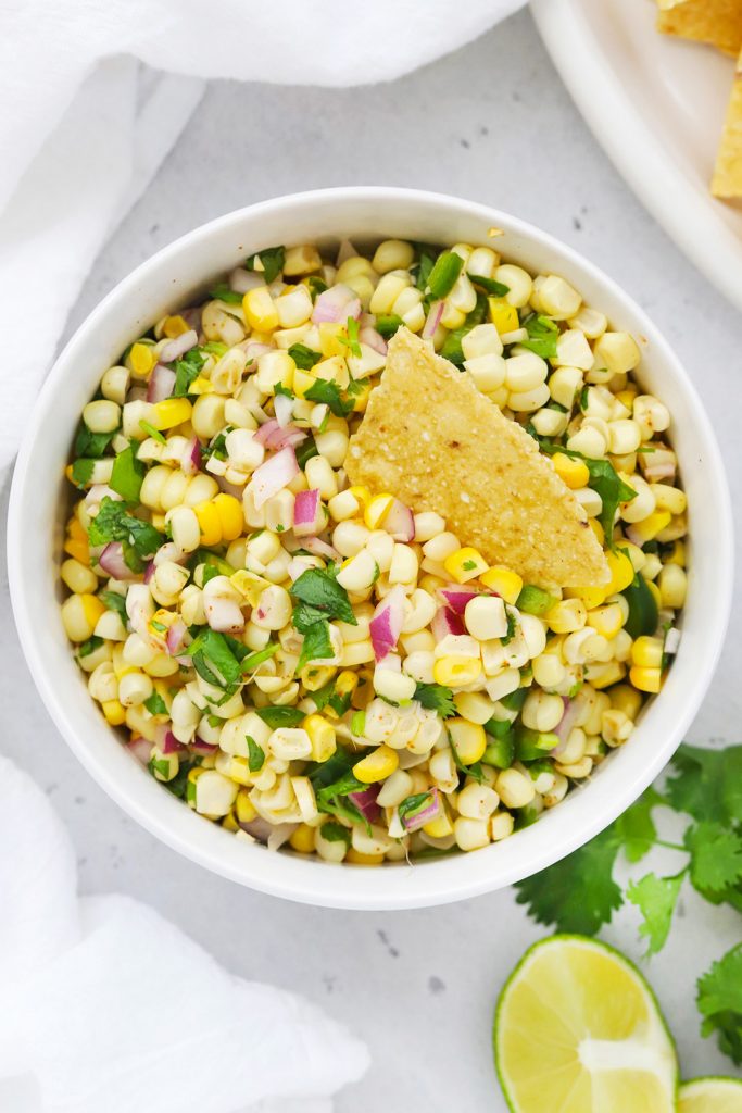 Close up overhead view of Chipotle Copycat fresh corn salsa with a tortilla chip dipped into it
