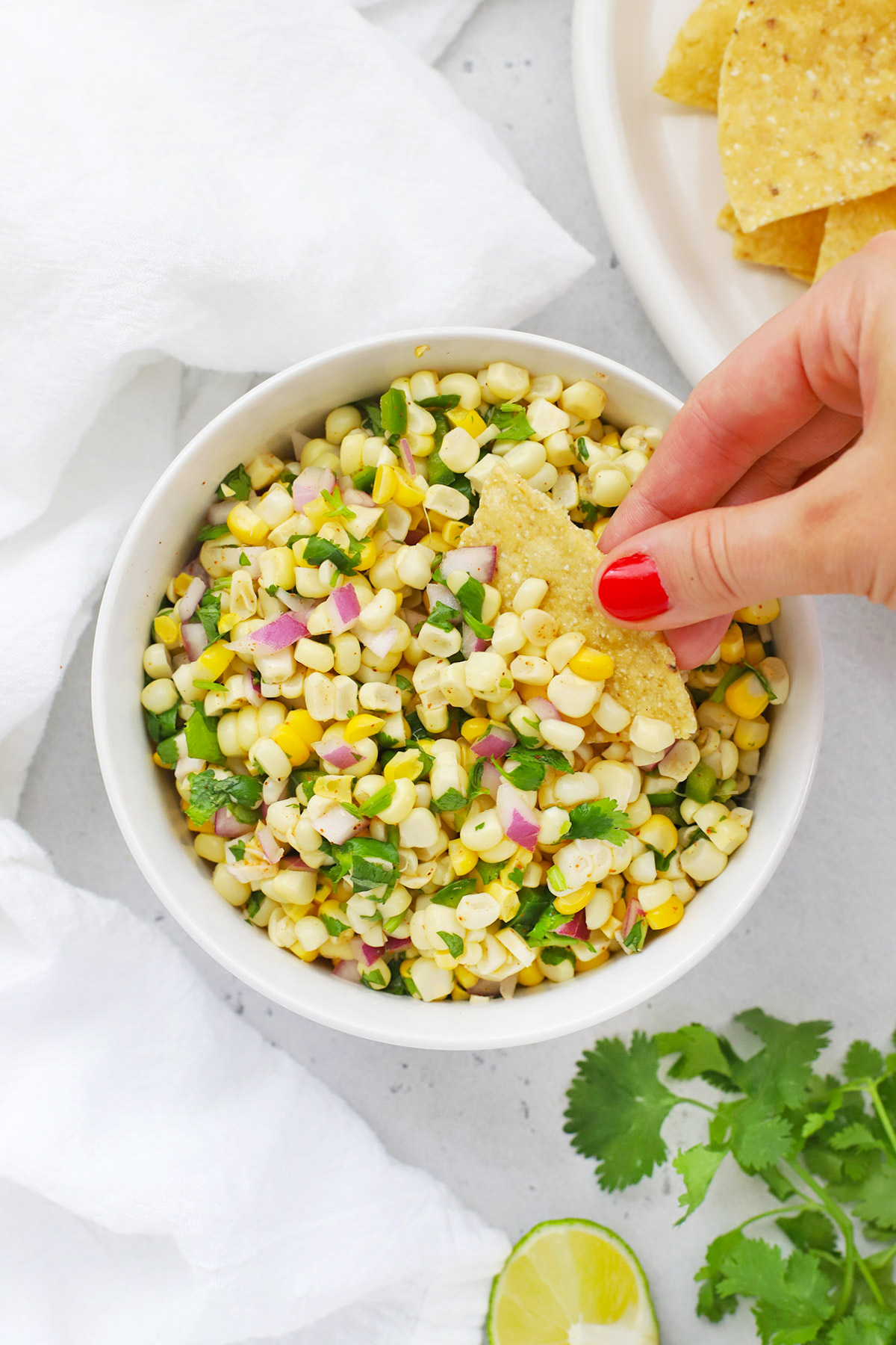 Overhead view of Chipotle Copycat fresh corn salsa with a tortilla chip dipped into it
