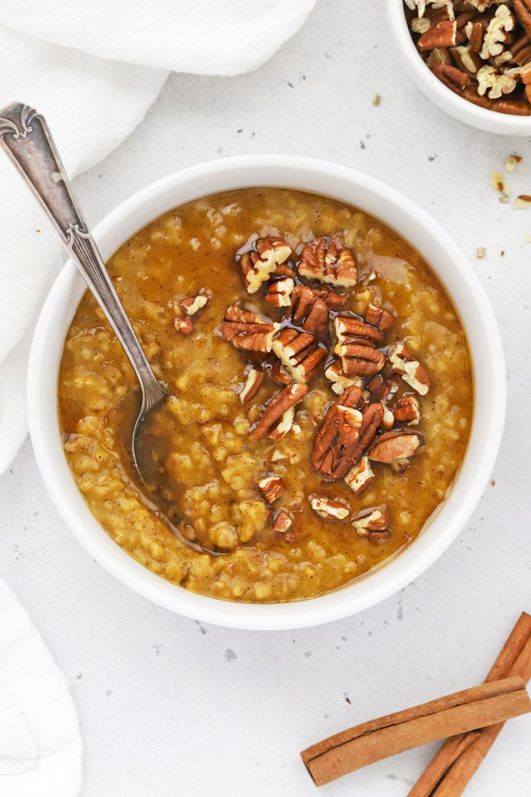 Close up overhead view of a bowl of Instant Pot Pumpkin Steel Cut Oats topped with maple syrup and pecans