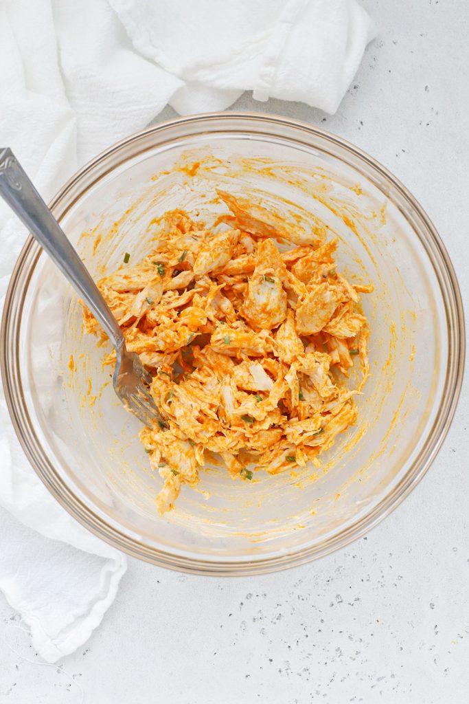 Overhead view of shredded chicken tossed with buffalo sauce, ranch, and chives