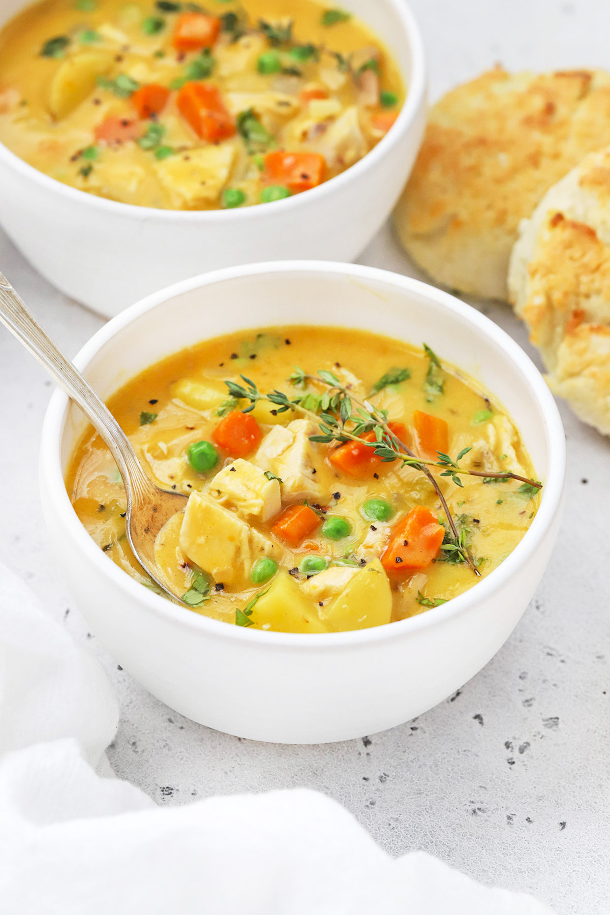 Front view of two bowls of healthy dairy-free chicken pot pie soup with gluten-free biscuits