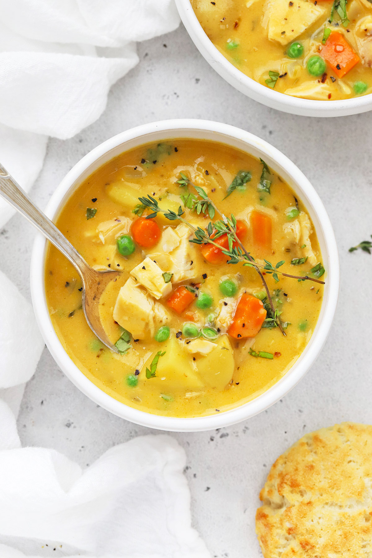 Overhead view of two bowls of healthy dairy-free chicken pot pie soup with gluten-free biscuits