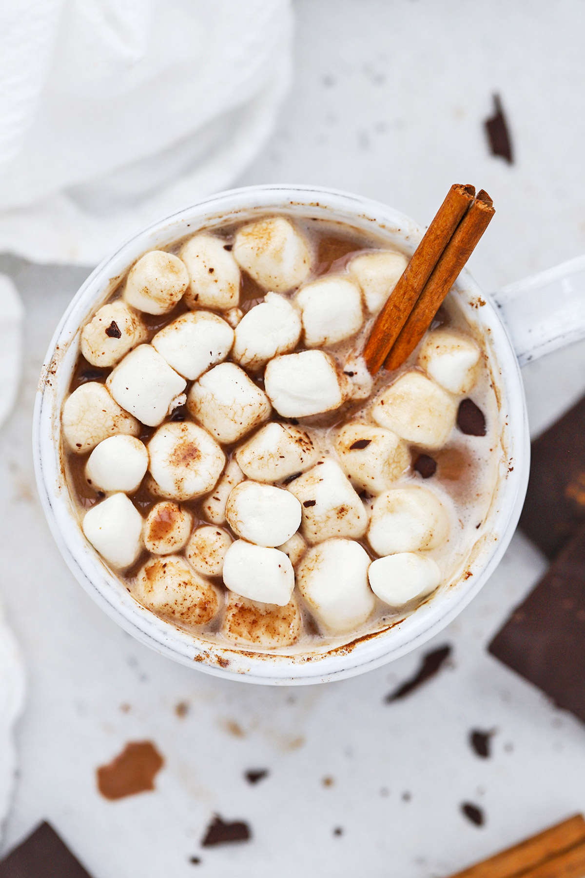 Overhead view of dairy free pumpkin spice hot chocolate topped with vegan marshmallows and a cinnamon stick