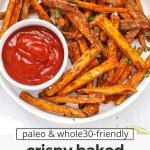 Crispy baked sweet potato fries on a white plate with a small bowl of ketchup