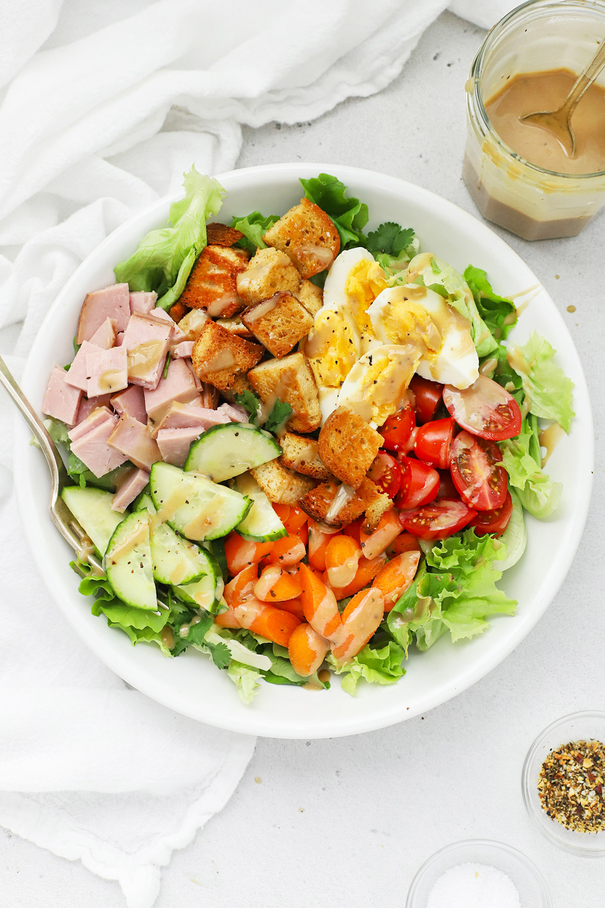 Overhead view of a colorful cobb salad served with homemade honey mustard dressing