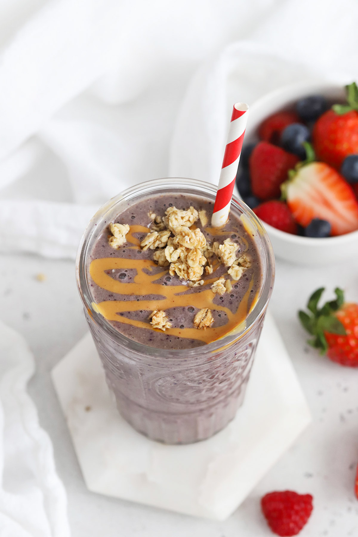 Front view of peanut butter jelly smoothie topped with peanut butter and granola