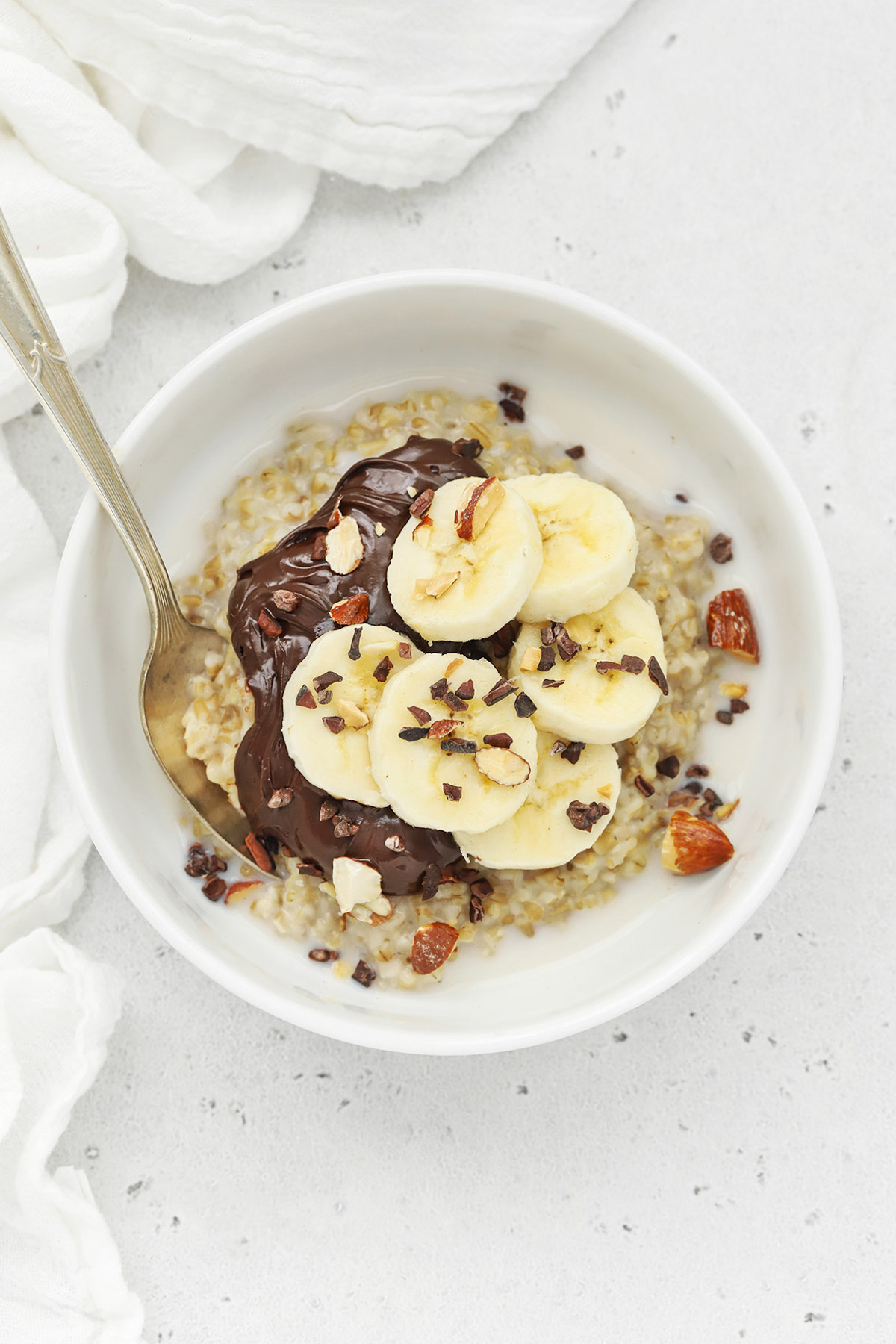 Overhead view of steel-cut oats topped with nutella, bananas, and chopped nuts