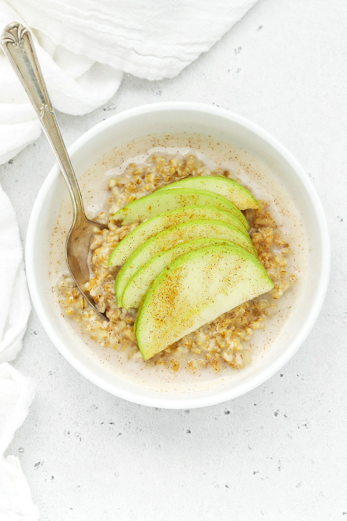 Overhead view of a bowl of steel-cut oats topped with cinnamon and sliced apples