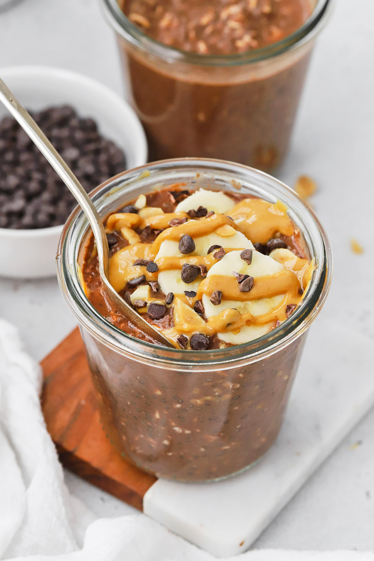 Front view of healthy chocolate peanut butter overnight oats with banana, peanut butter, and cacao nibs
