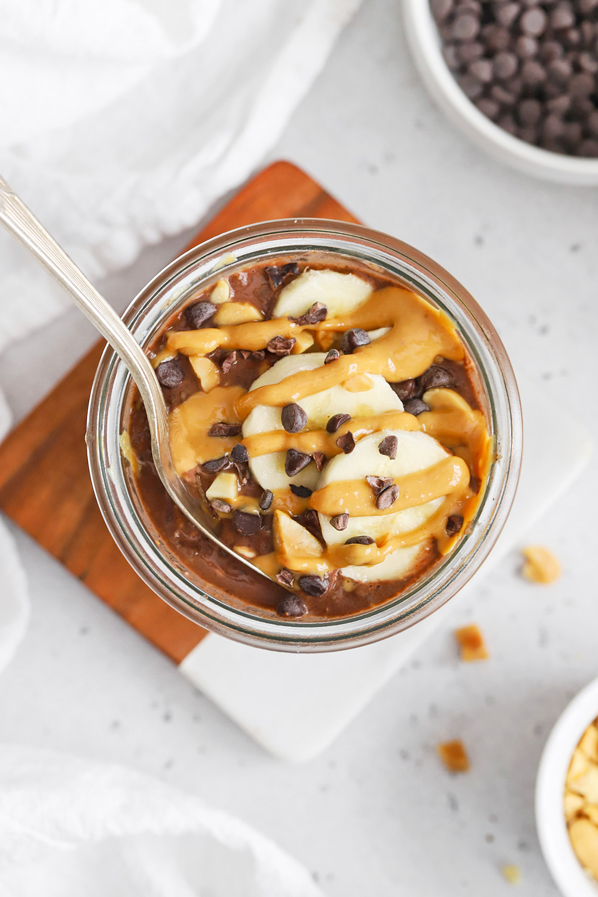 Overhead view of vegan chocolate peanut butter overnight oats drizzled with peanut butter and topped with banana slices and cacao nibs