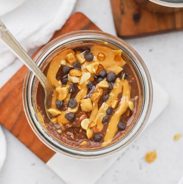 Overhead view of vegan chocolate peanut butter overnight oats drizzled with peanut butter and topped with chopped peanuts and cacao nibs