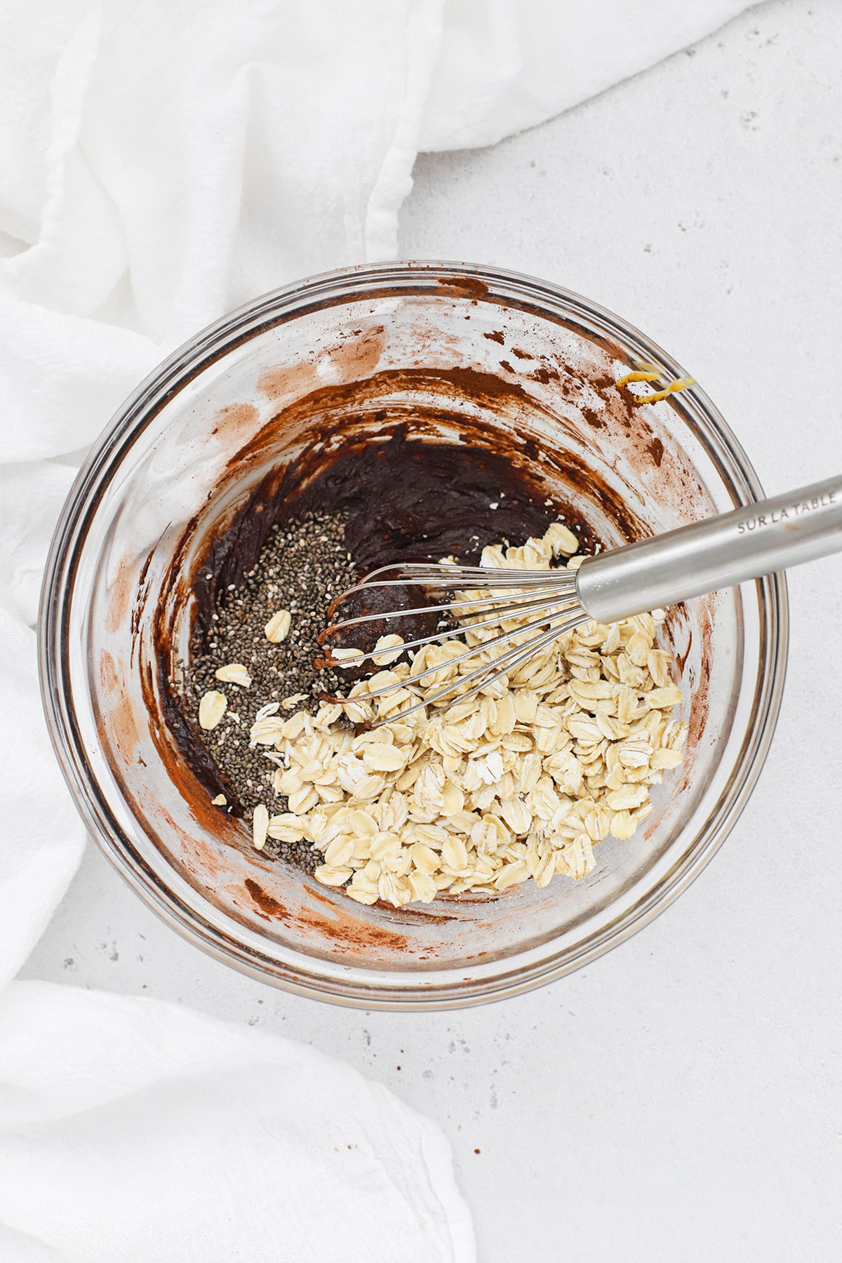 Adding oats and chia seeds to a chocolate peanut butter mixture to make peanut butter cup overnight oats