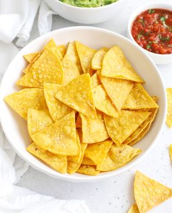 Overhead view of homemade baked tortilla chips with salt, served with salsa & guacamole