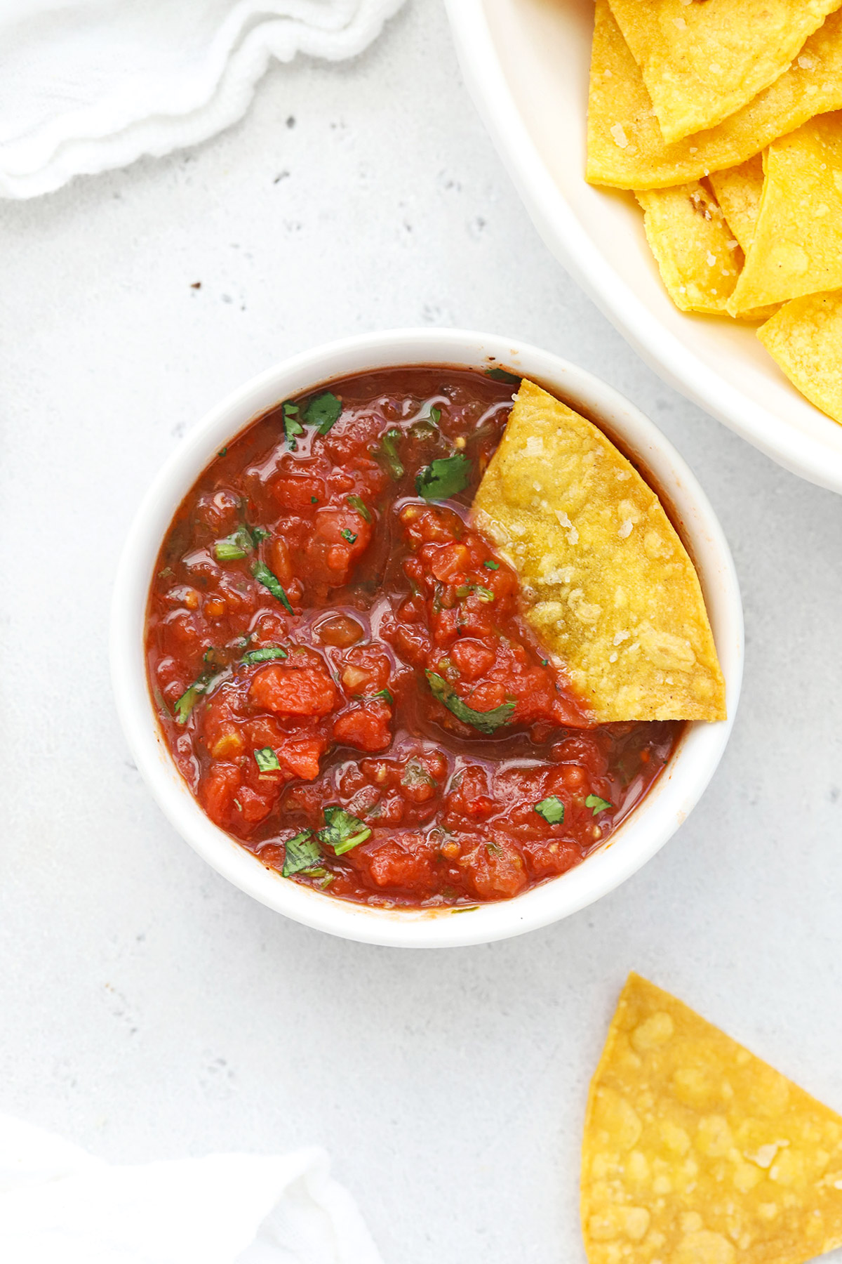 Overhead view of a bowl of salsa with healthy baked tortilla chips