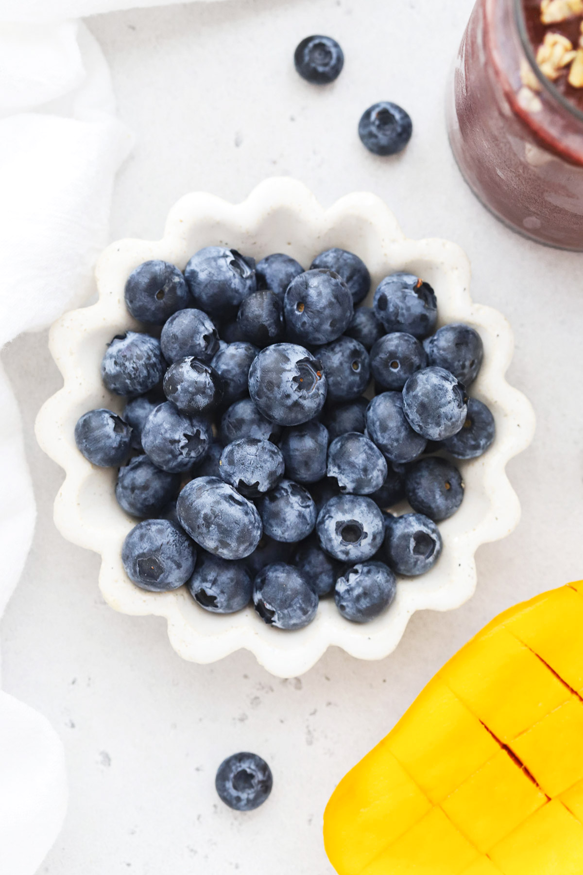 Overhead view of a ruffled white bowl of fresh blueberries