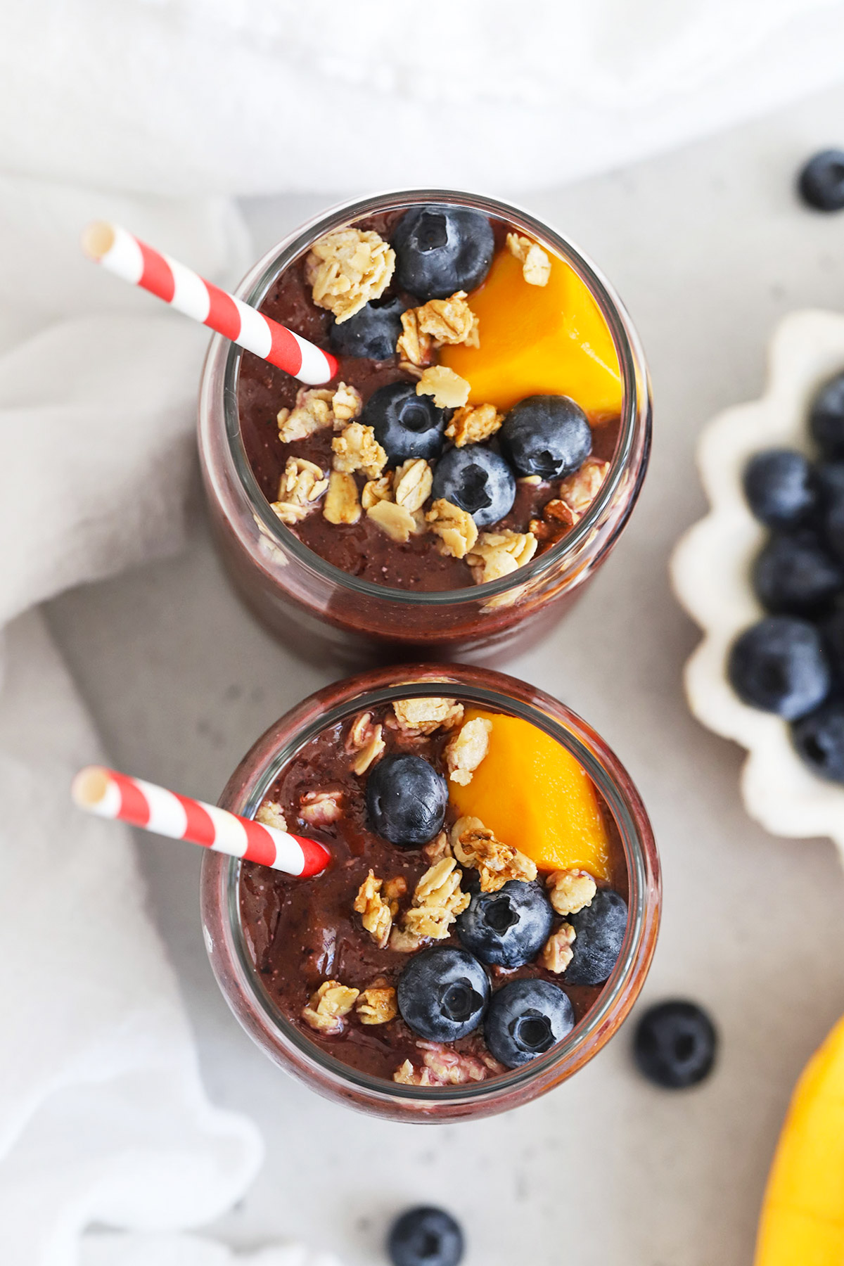 Overhead view of two glasses of blueberry mango smoothies topped with fresh fruit