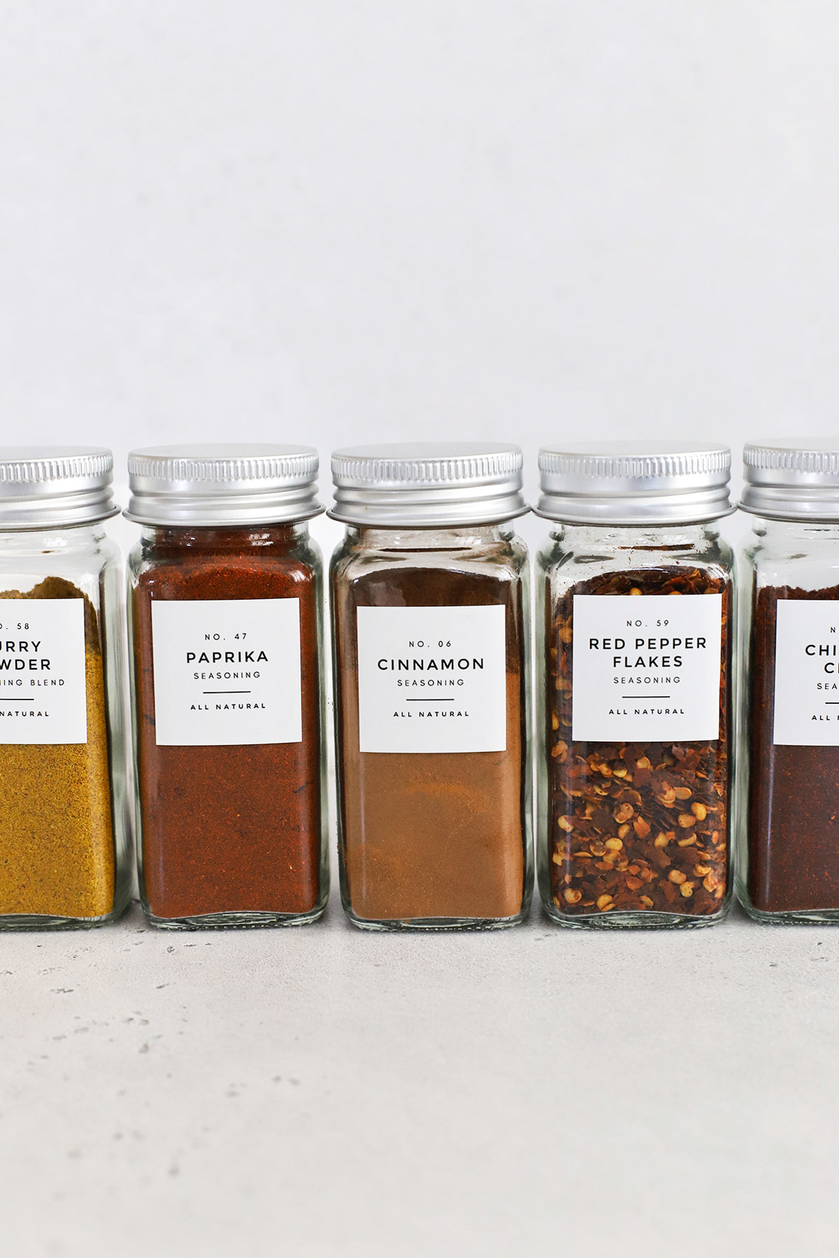 A row of organized spice jars with minimalist labels