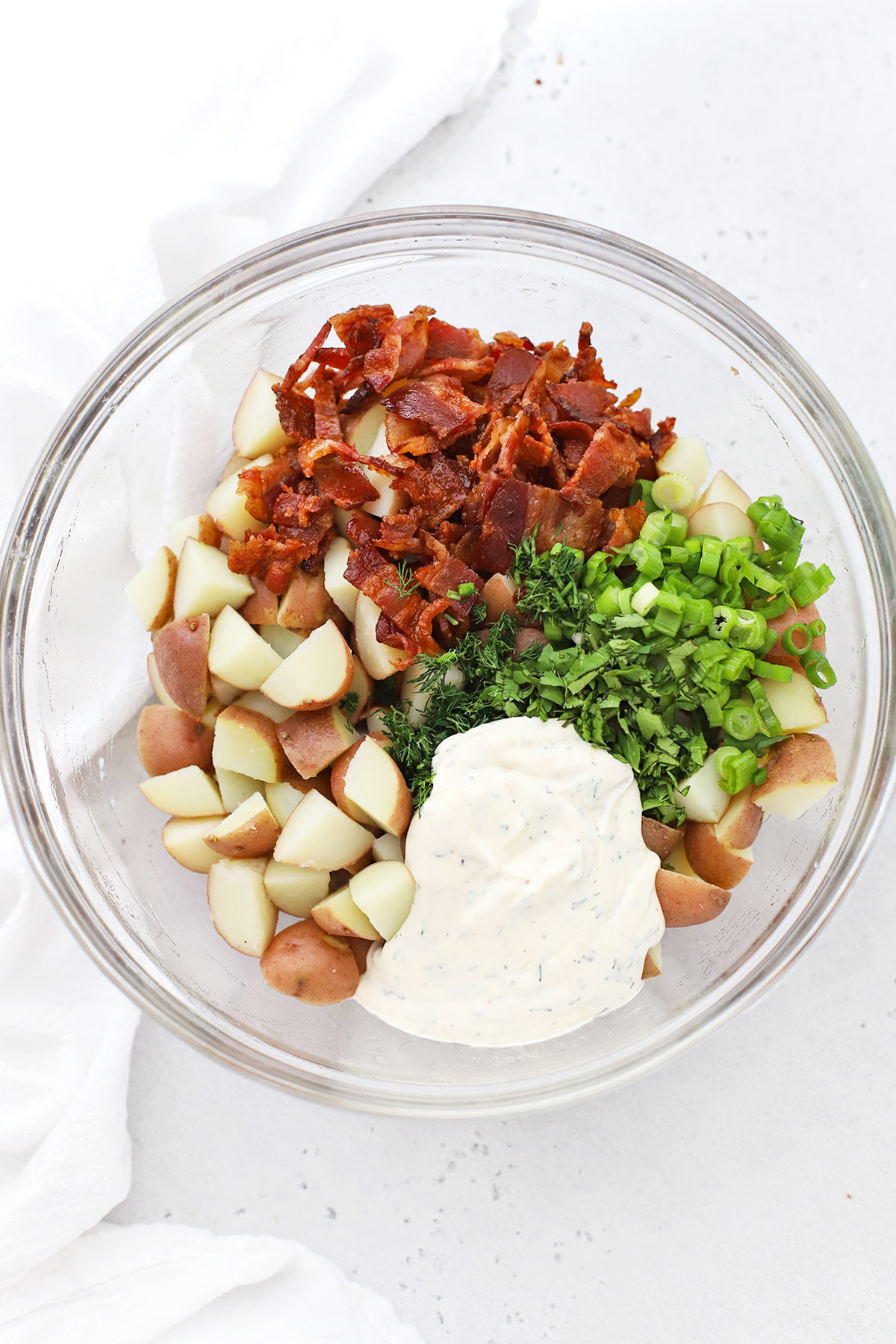 Ingredients for bacon ranch potato salad in a glass bowl