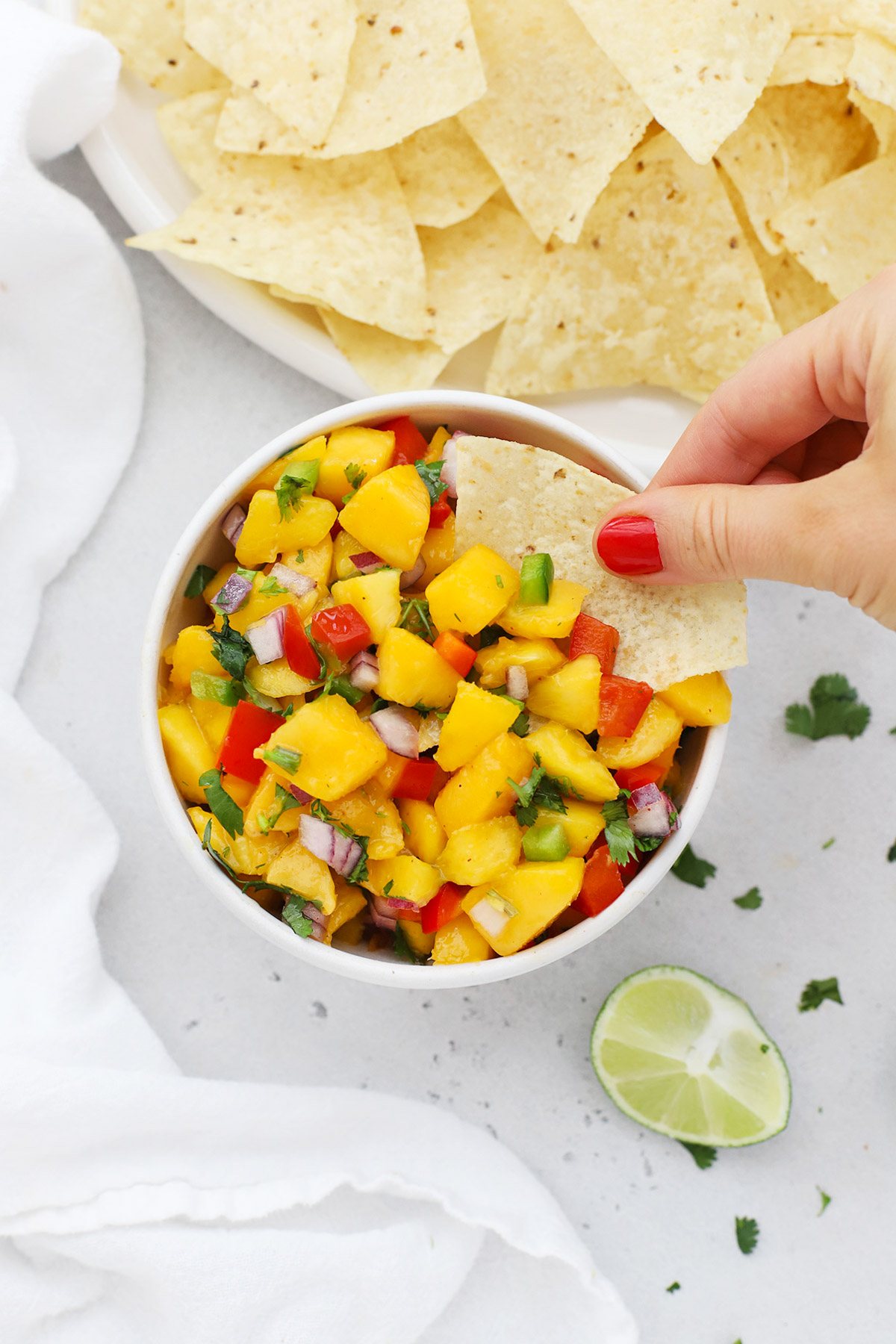 Dipping a chip into a bowl of peach salsa