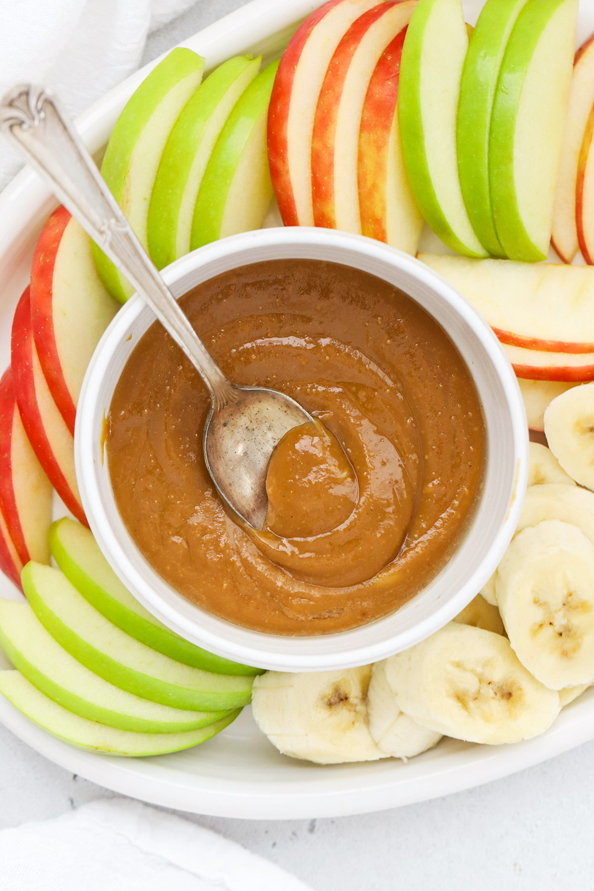 overhead view of a bowl of healthy peanut butter caramel dip in a bowl with a spoon
