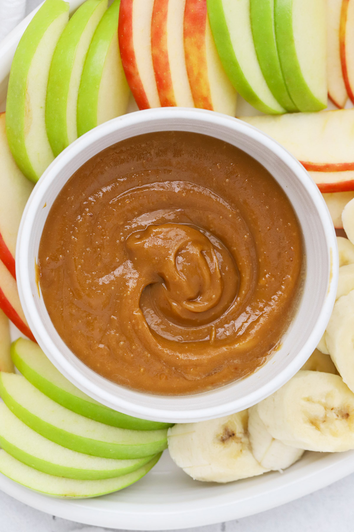 Overhead view of a bowl of peanut butter caramel dip with fresh fruit