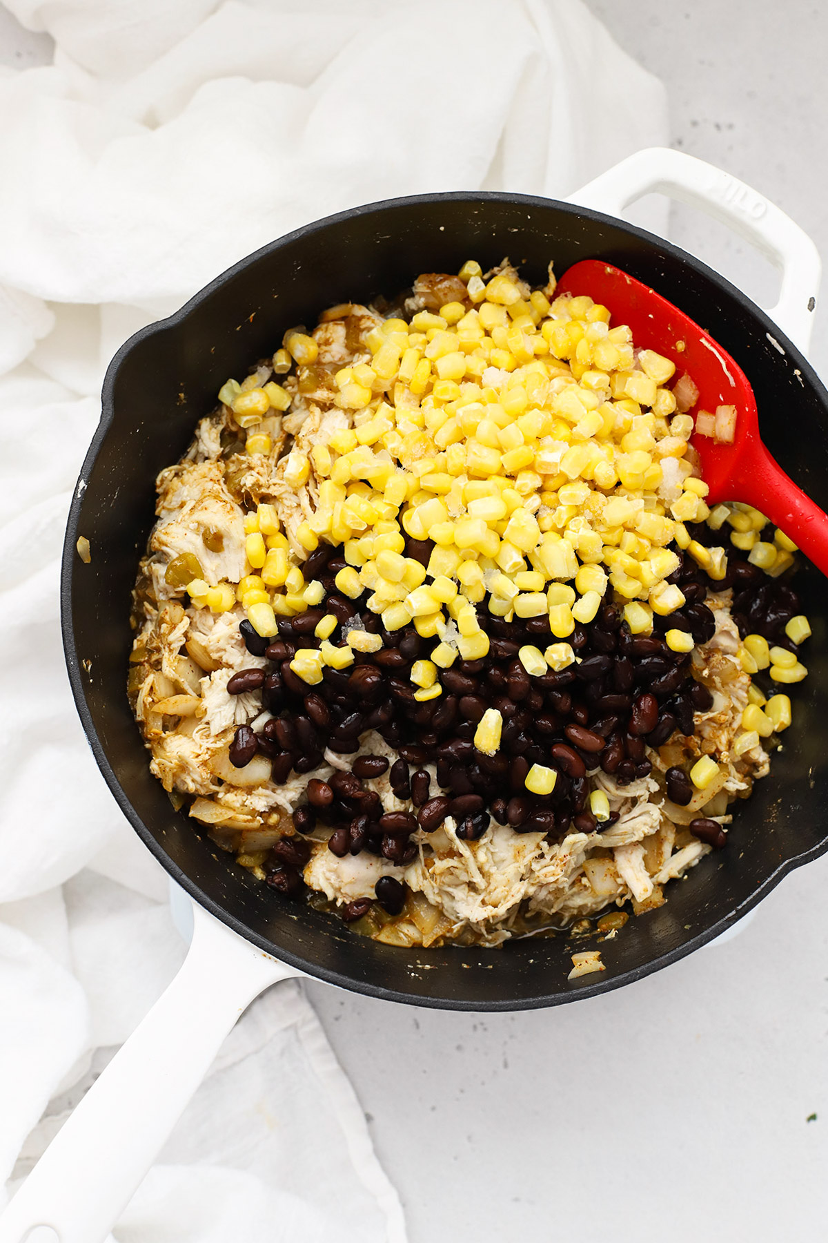 Adding corn, black beans, and chicken to a skillet