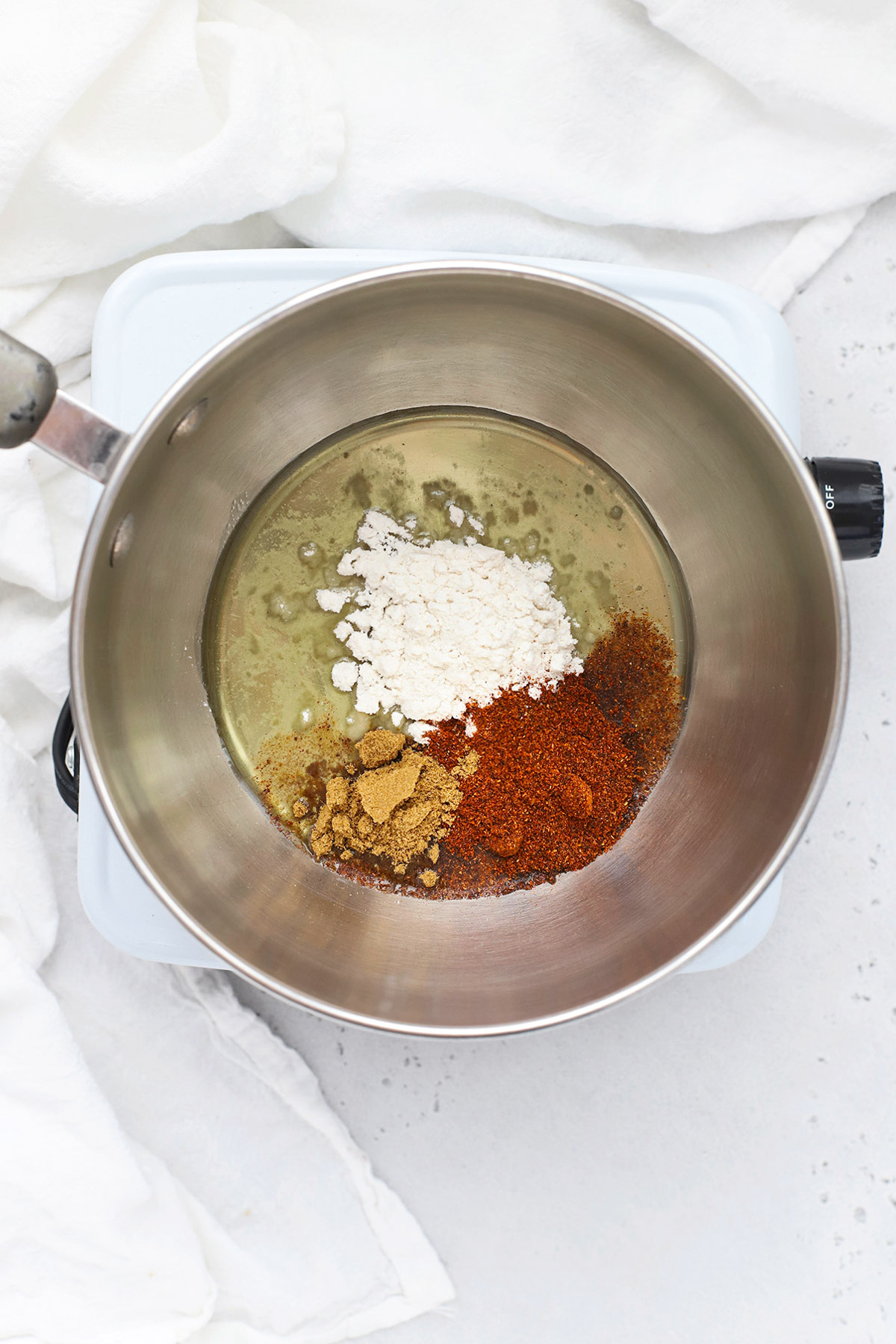 Overhead view of spices, cornstarch, and oil in a saucepan to make gluten free enchilada sauce