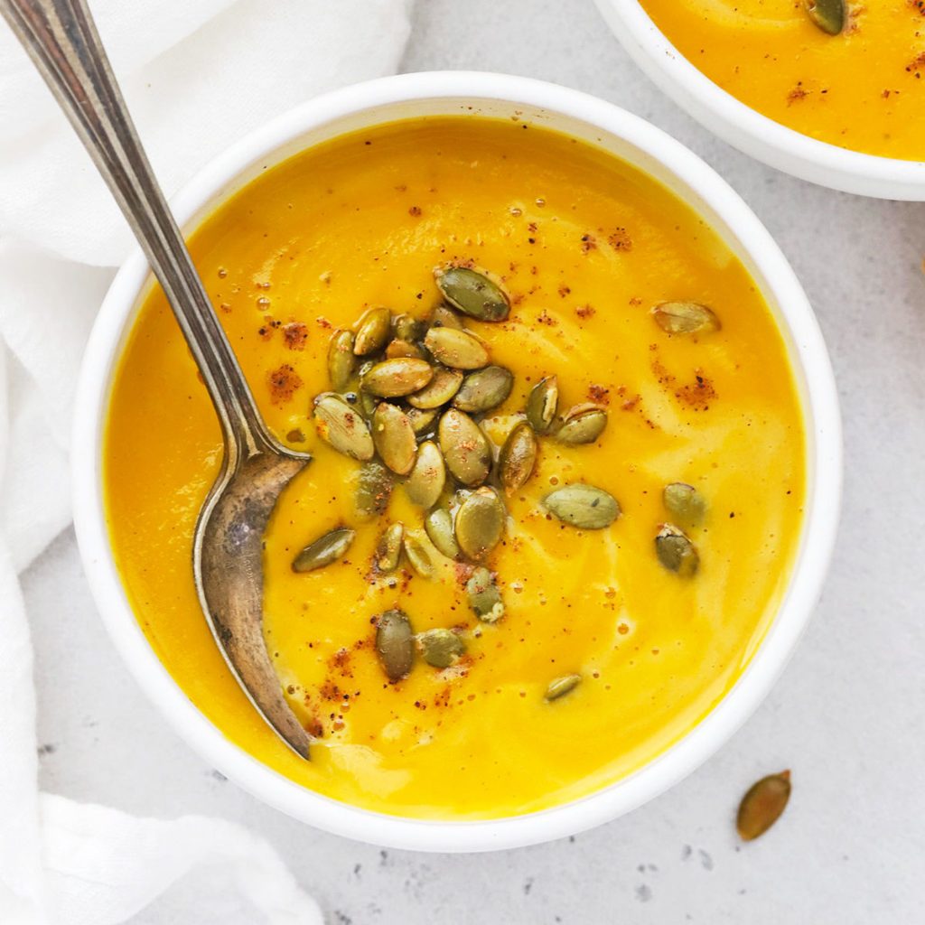 overhead bowl of Panera Copycat autumn squash soup topped with pumpkin seeds