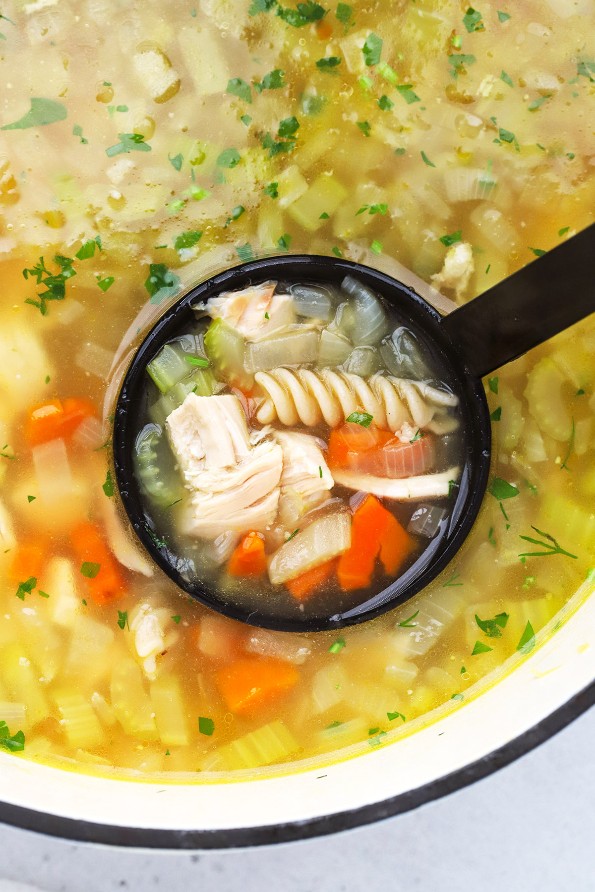 A black ladle scooping up gluten-free chicken soup