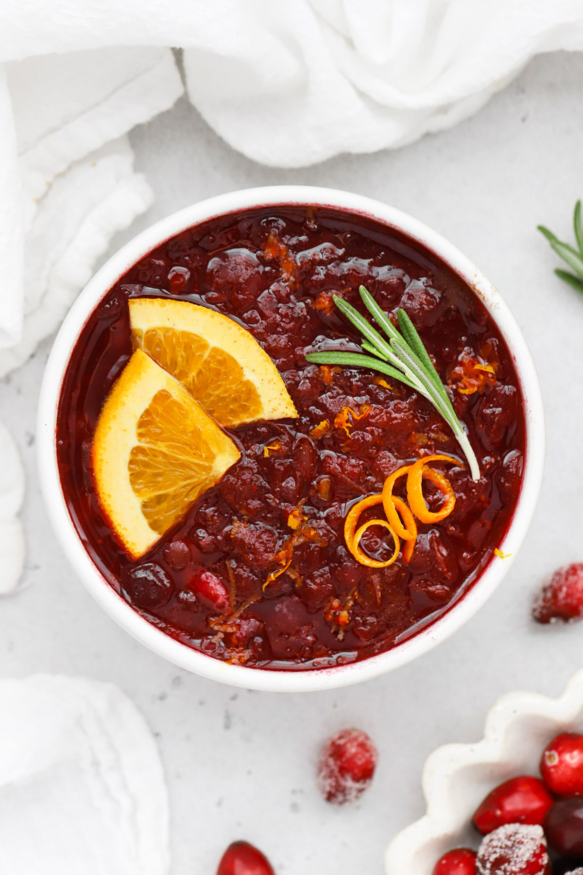 overhead view of a bowl of instant pot cranberry sauce garnished with orange slices and rosemary