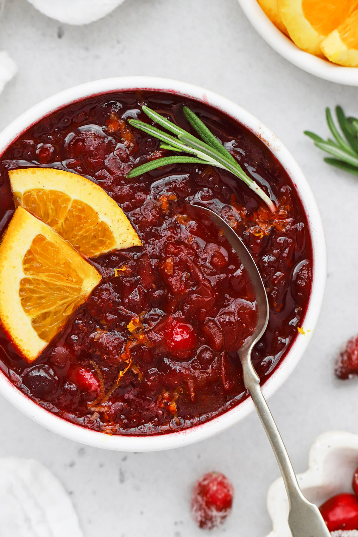 overhead view of a bowl of instant pot cranberry sauce garnished with orange slices and rosemary