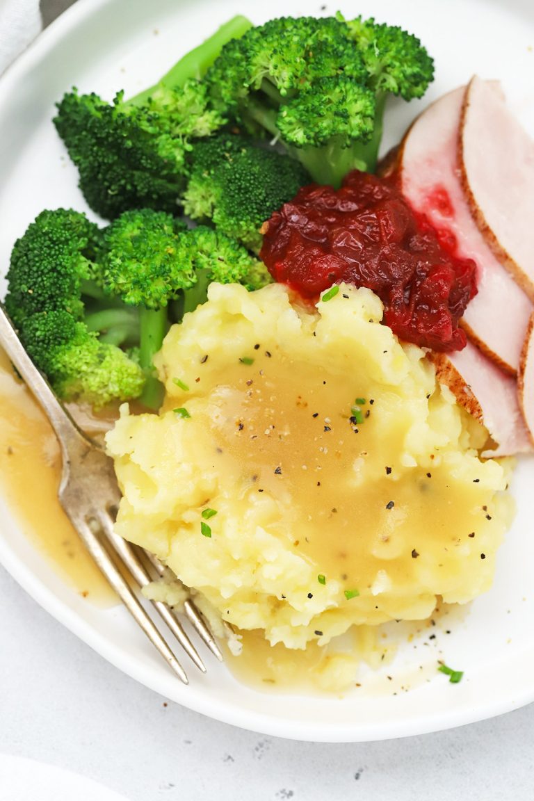 Overhead view of a plate of slow cooker mashed potatoes, broccoli, turkey, and cranberry sauce