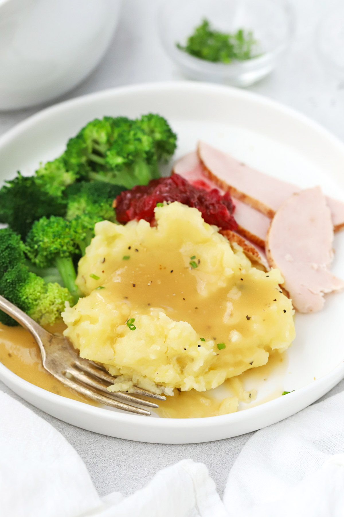 Front view of a plate of slow cooker mashed potatoes with gravy, broccoli, turkey, and cranberry sauce
