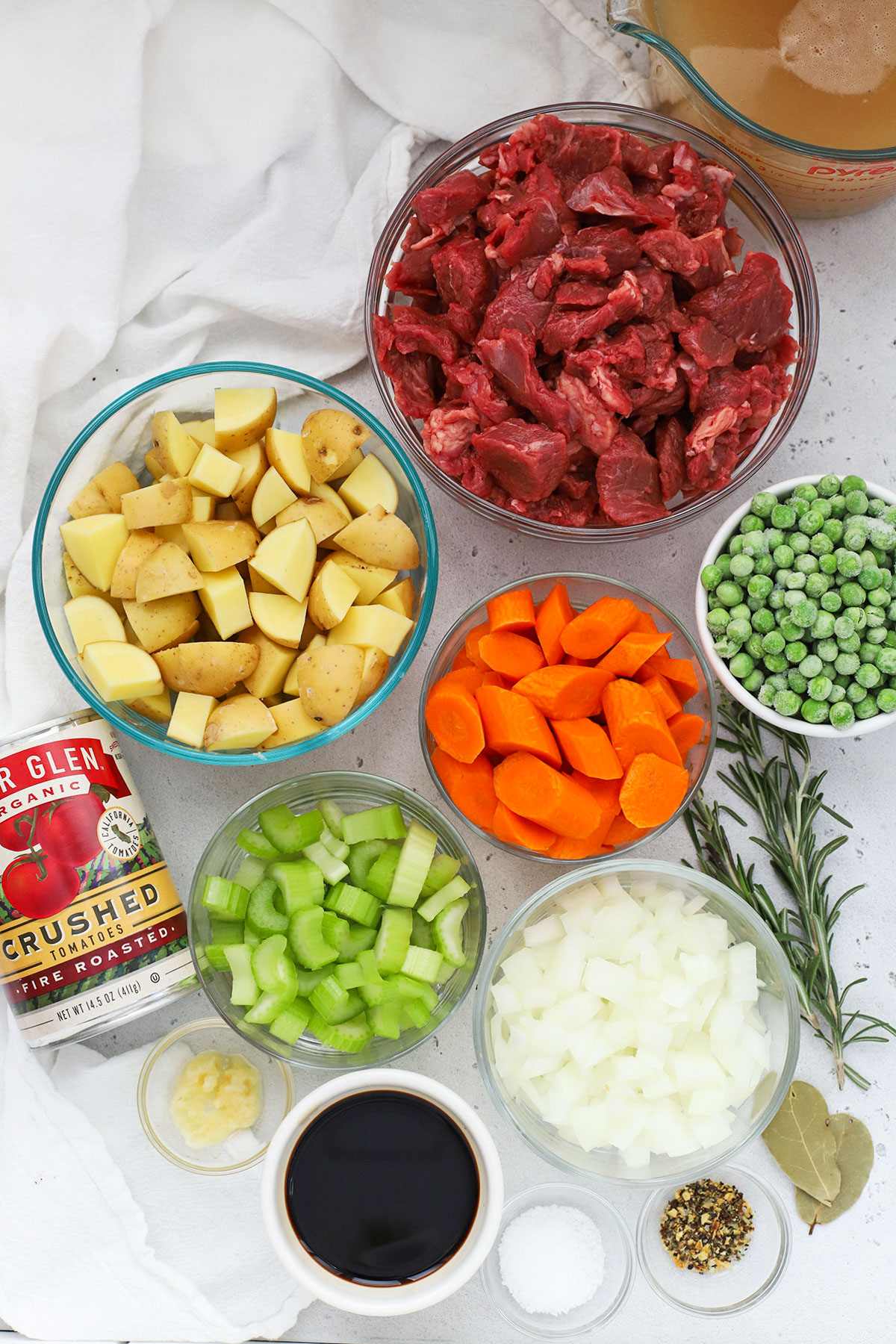 Ingredients for gluten-free beef stew in small glass and white bowls