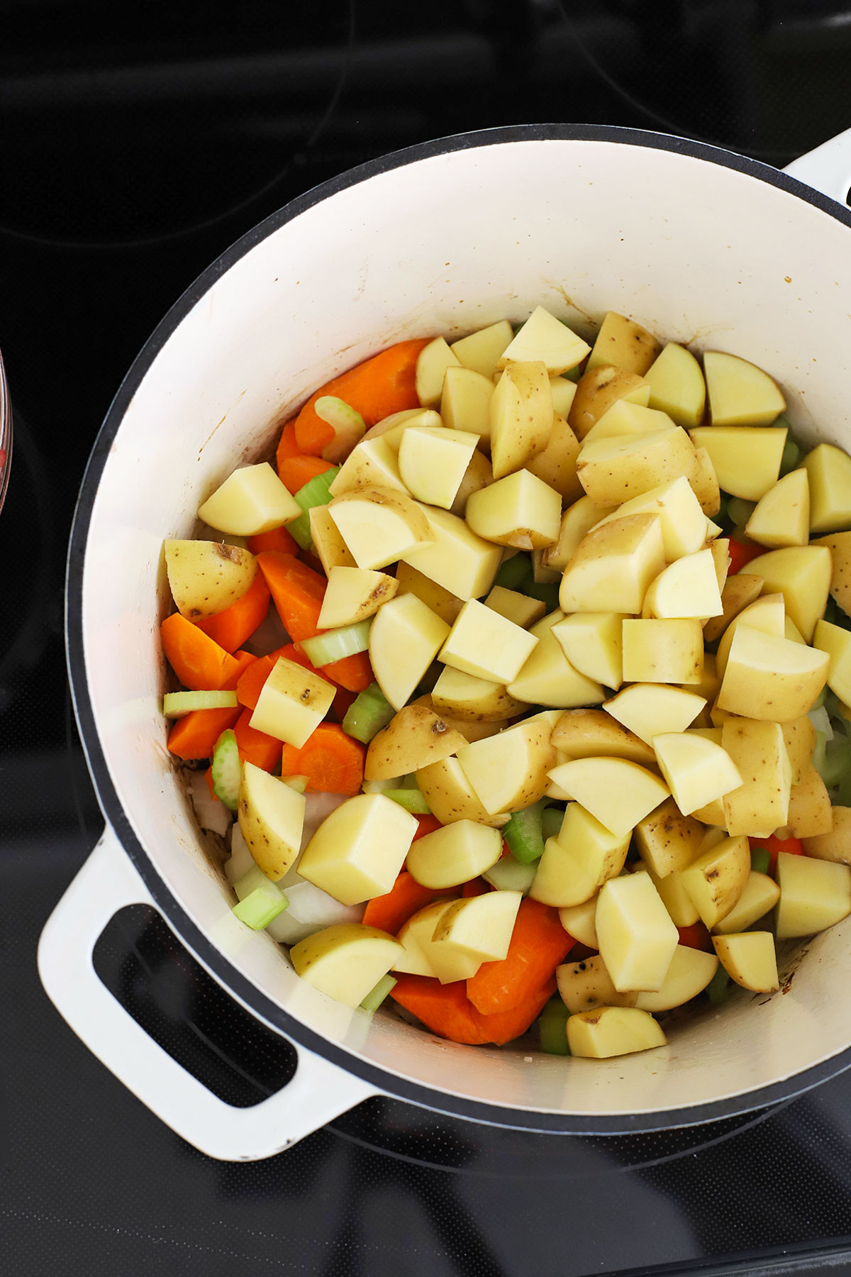 Adding vegetables to a white Dutch oven