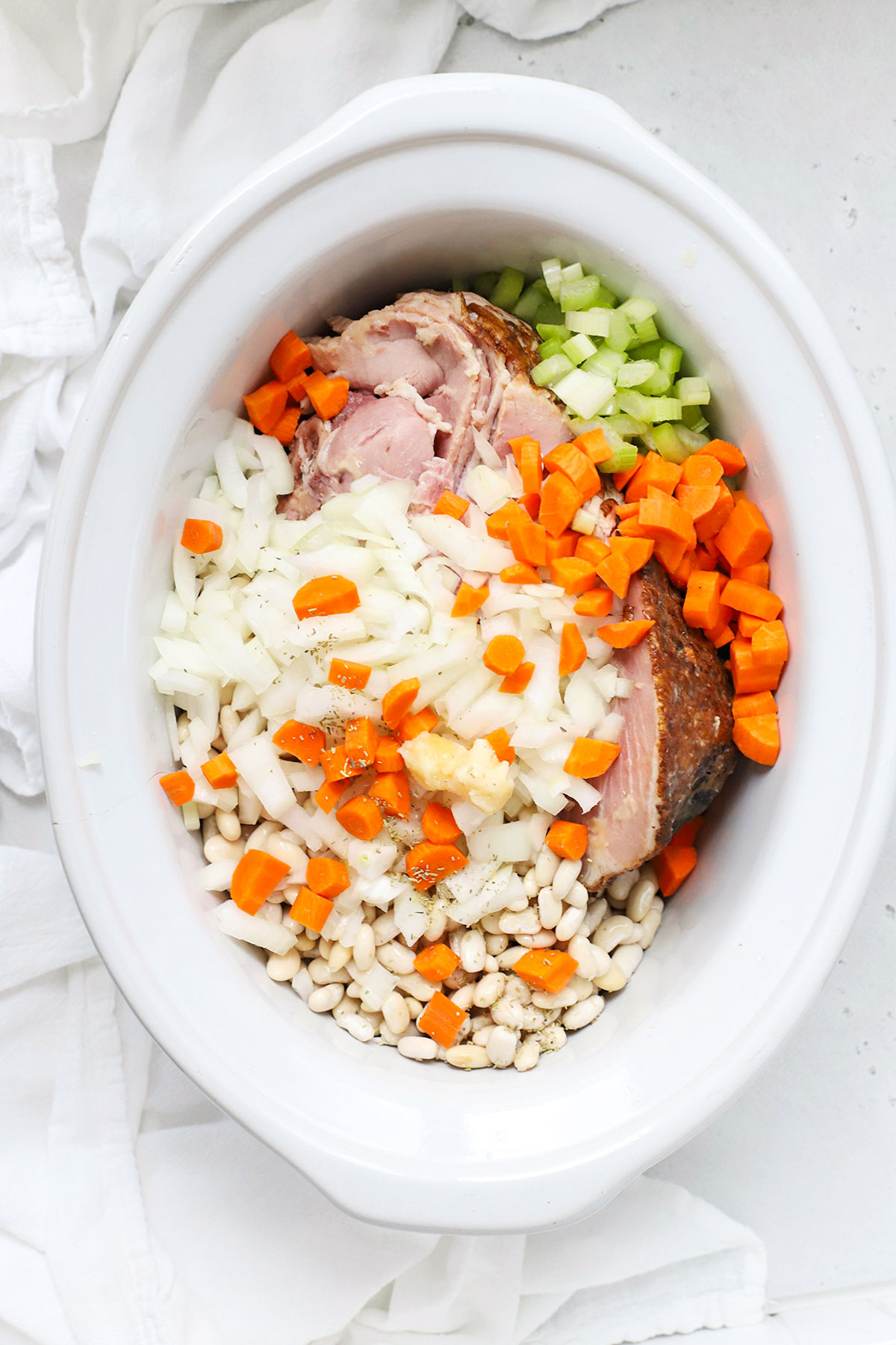 overhead view of ingredients for slow cooker ham bean soup in a crock pot
