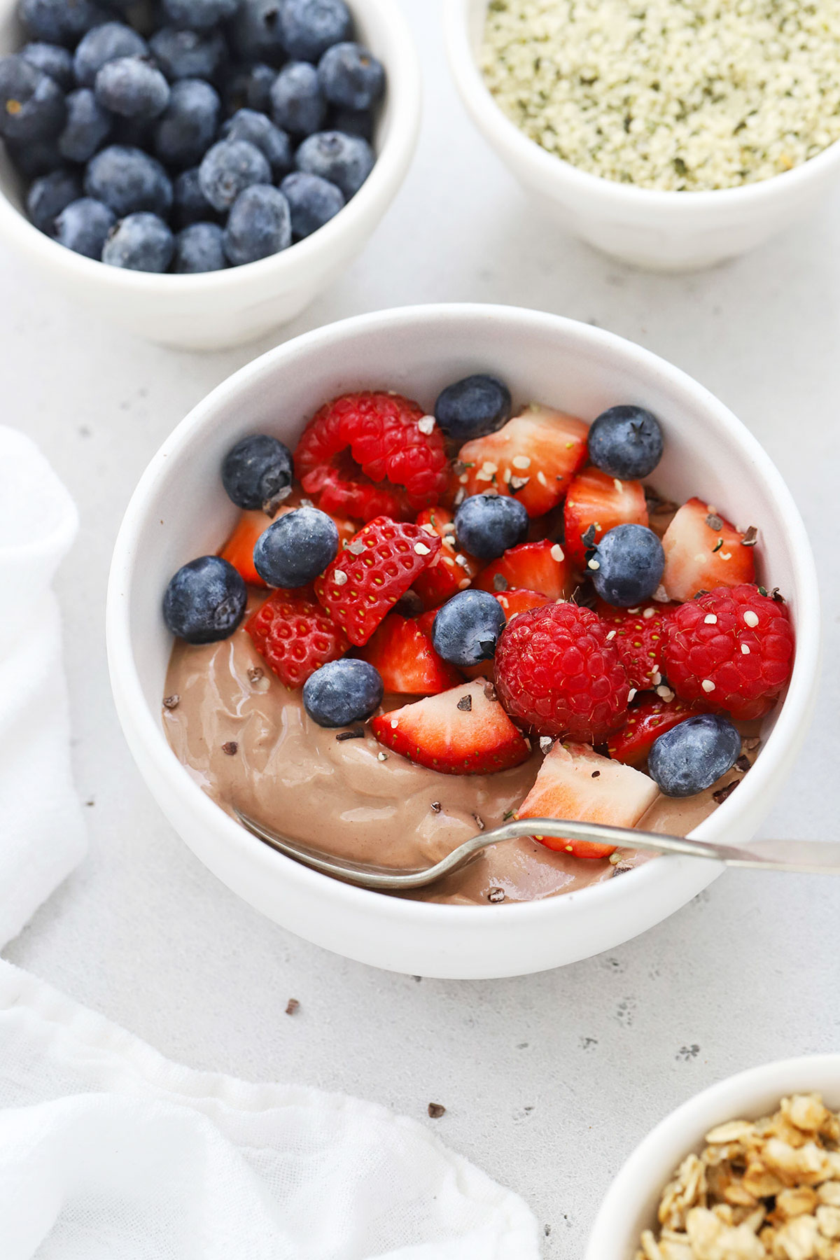 High protein chocolate yogurt bowl topped with fresh berries, hemp seeds, and cacao nibs