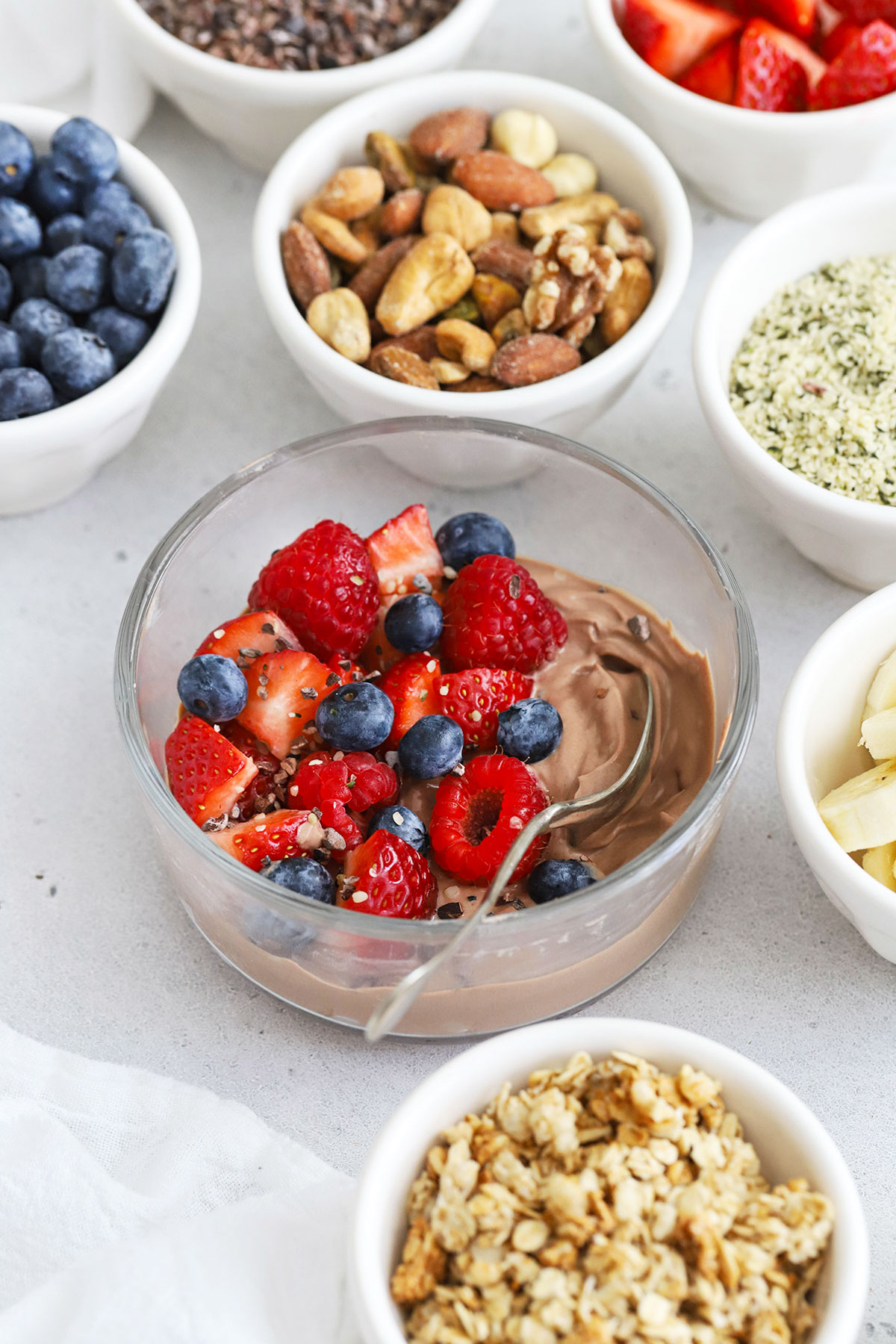 Adding toppings to chocolate protein yogurt bowls