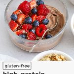 High protein chocolate yogurt bowl topped with fresh berries, hemp seeds, and cacao nibs