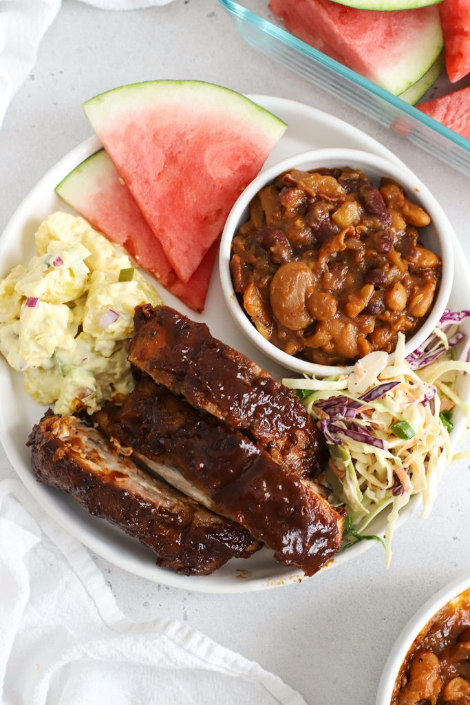 slow cooker bbq ribs with four different side dishes on a white plate