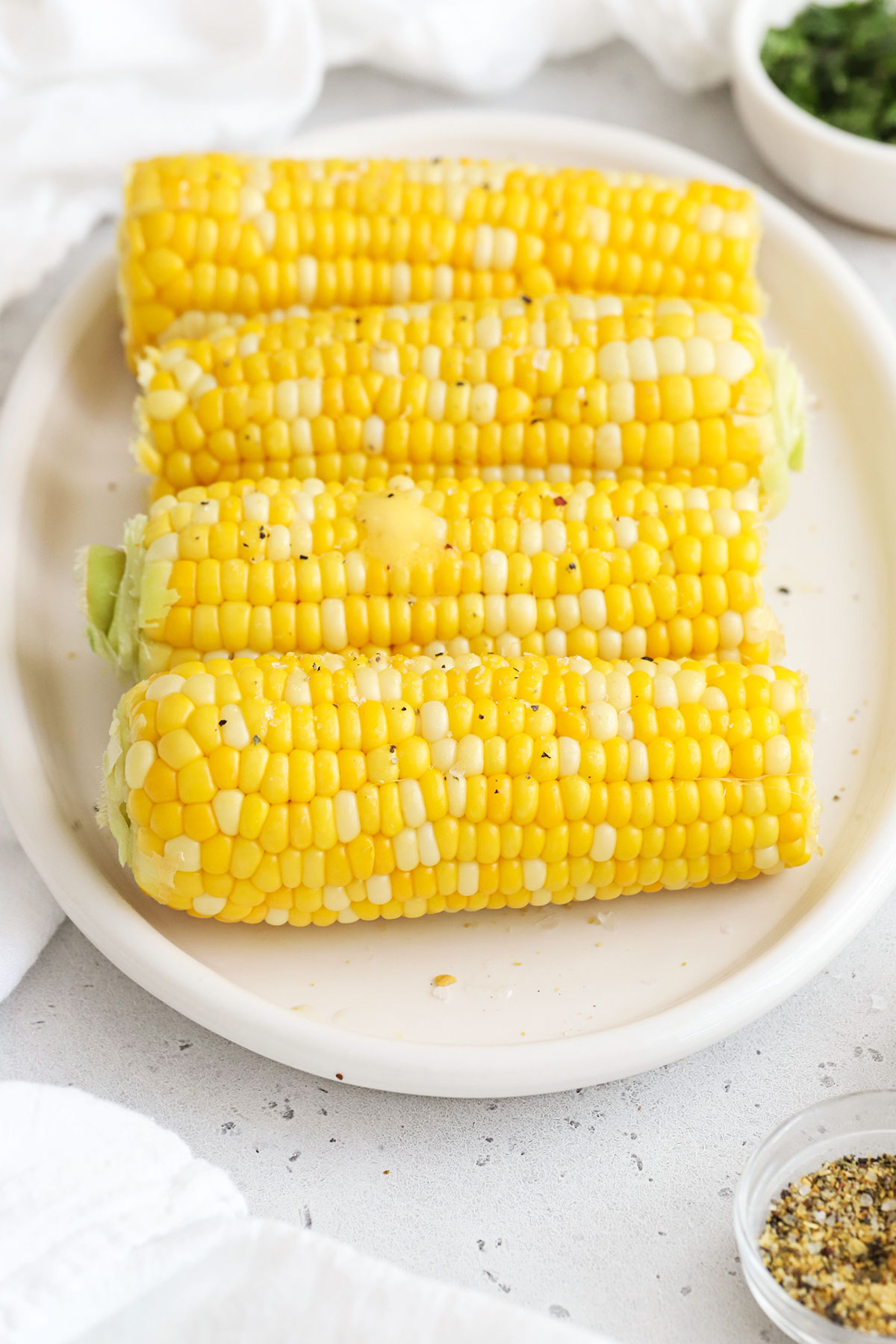 4 ears of boiled corn on the cob on a white platter