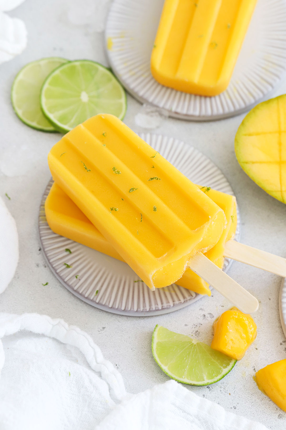 two mango lime popsicles stacked on a coaster