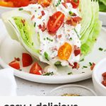 wedge salad with parmesan dressing, bacon, and tomatoes on a white plate