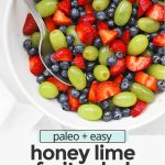colorful honey lime fruit salad with green grapes, strawberries, and blueberries